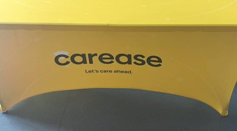 Yellow 180 gsm stretch table cover printed with a client logo on a 6 ft trestle table