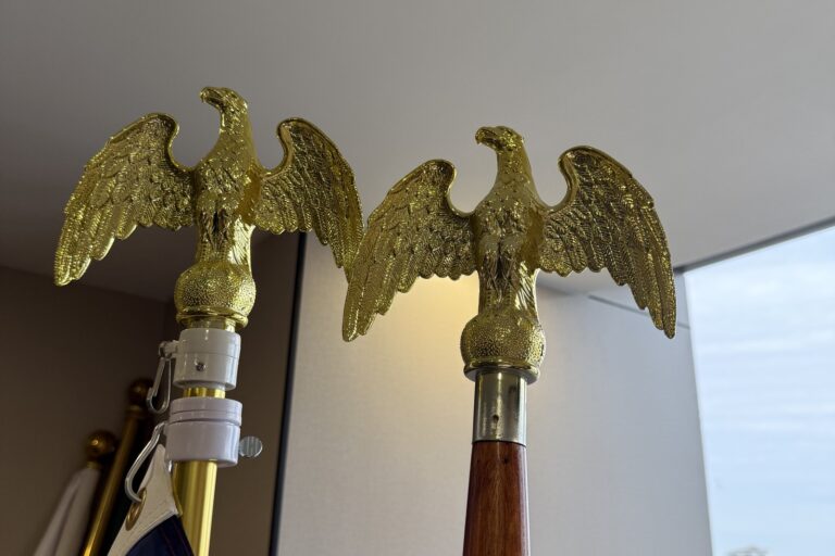 Golden eagle head finial on a wooden indoor flagpole and on a metal indoor flagpole